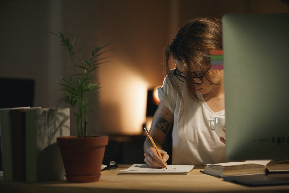 Una persona estudiant a casa amb ordinador i quadern